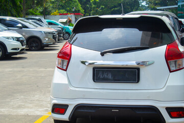 back view of white honda jazz car parked in a row in outdoor area with yellow line on the gorund...