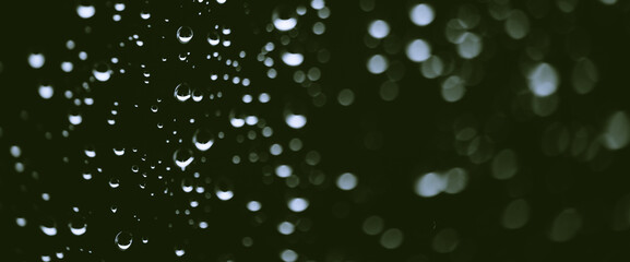 Atmospheric minimal monochrome backdrop with rain droplets on glass. Wet window with rainy drops and dirt spots closeup. Blurry minimalist background of dirty window glass with raindrops close up.