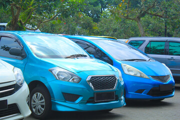 hatchback car with aqua and blue color parked in a row with trees background