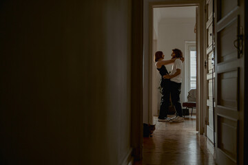 Smiling couple hugging and enjoying time together while standing at home. Good relationship time