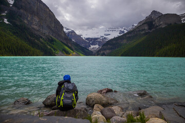 Panorama of Lake Louise, Banff National Park, Alberta, Canada. Lifestyle Travel - Backpack hiker sitting by Lake, relax and looks on amazing landscape. Active life. 