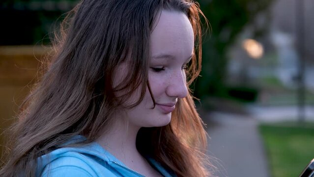 face of beautiful young girl looking at phone turn head look into camera close-up tenderness modesty purity beauty virginity straighten hair embarrassment sincerity in eyes of adolescence teenager