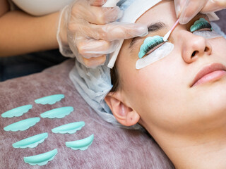 The master removes the composition for lamination from the client's eyelashes with a cotton swab. Eyelash perm procedure.