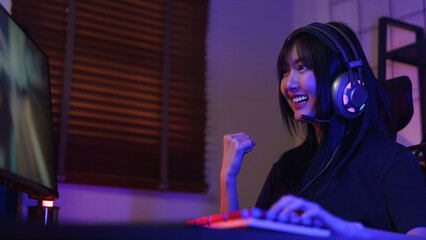Female cyber hacker gamer in headphones making win gesture after hacking programming system success