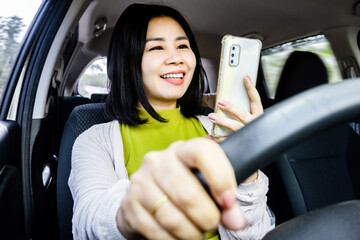 careless Asian woman using a mobile phone and not wearing a seat belt while driving on the road, Risky driving habits concept