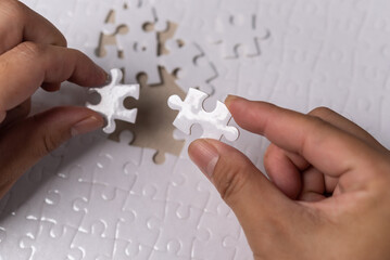hands of businessmen joining white jigsaw pieces. Business concept.