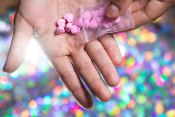 Man pouring heart shaped pills on palm from ziplock bag.