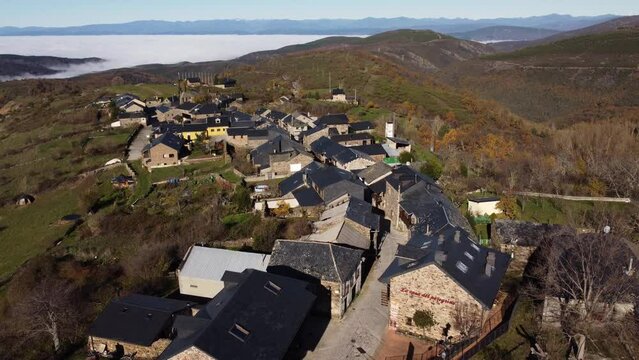 Aerial view of a charming mountain village emerging from clouds