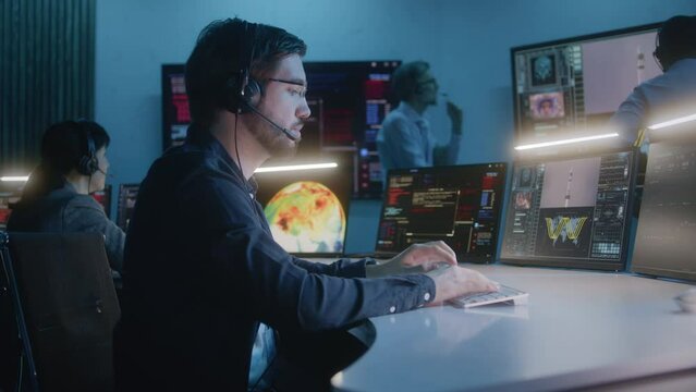 Flight control worker in headset monitors space mission with astronaut on multi-monitor computer in command center. Team clap hands and watch successful space rocket launch on big digital screens.