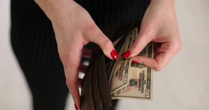 Woman hand takes out and counts American banknotes from purse. Financial control of expenses