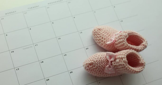 Waiting for baby and pink shoes for newborns and calendar. Planning for pregnancy and childbirth