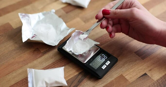 Persons weigh white powder on an electronic scale. Drug dealer pack up a dose of drugs
