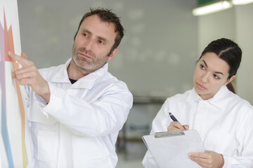 Obraz premium man painting the wall while apprentice taking notes
