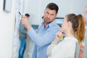 teacher showing wall notice to apprentice