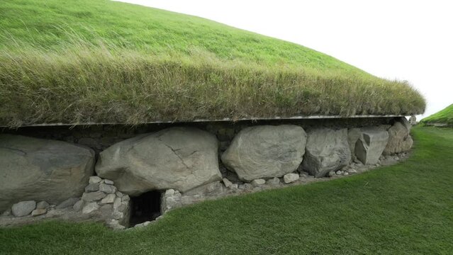 Wind blowing grass on Irish stone age tomb over entrance