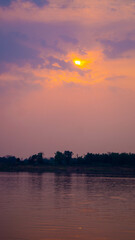 Silhouette of a guy in the water, with a vivid orange and pink sunset, Thakhek loop, Laos