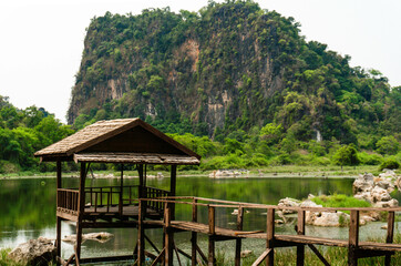 Fototapeta na wymiar Luxurious mountain with vegetation next to a lake, with a little wooden hut and a bridge, Thakhek loop, Laos