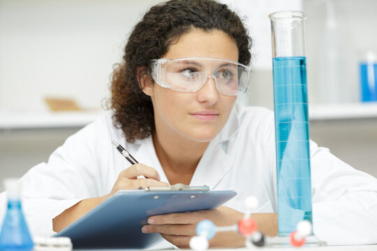 Girl With Protective Glasses In A Lab Writes Notes