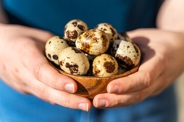 Girl holding a wooden bowl with fresh quail eggs. 