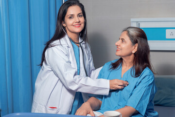 Indian female doctor using a stethoscope for check up on bed at hospital.