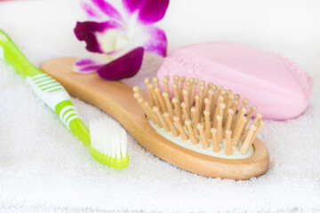 toothbrush, comb, soap health care with flower arrangement flat lay style on bath towel