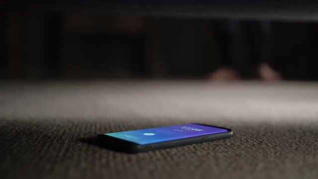 Guy looking for lost mobile phone under sofa