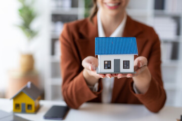 Female employee offering homes to client with contract and insurance. Real estate agent offering house or condo to client and contract and insure.