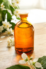 Small glass bottle of jasmine tincture(water infusion, extract, perfume). Jasmine essential oil. Fragrant flower for perfumery, cosmetics production. Side view, copy space for text, product place.