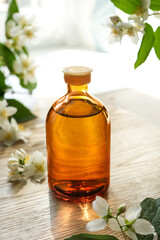 Small glass bottle of jasmine tincture(water infusion, extract, perfume). Jasmine essential oil. Fragrant flower for perfumery, cosmetics production. Side view, copy space for text, product place.