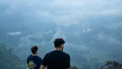 Two guys looking at mountains, on the top of a hills with a mysterious fog, in Vang Vieng, Laos"