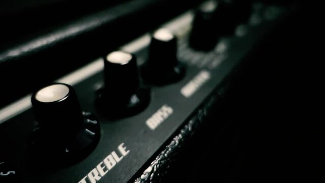 Cinematic shot of top of a black guitar amplifier. treble, bass knobs. India