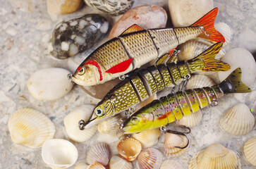 Three solid-bodied spinning baits against the background of sea stones.