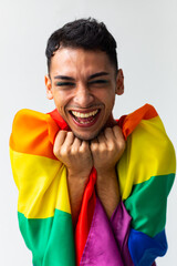 Portrait of happy biracial transgender man holding rainbow flag on white background