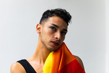 Thoughtful biracial transgender man holding rainbow flag on white background