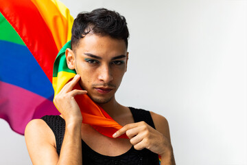 Portrait of biracial transgender man holding rainbow flag on white background, copy space
