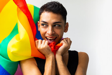 Portrait of happy biracial transgender man holding rainbow flag on white background, copy space