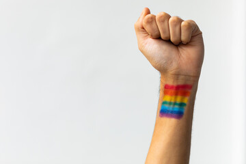 Close up of hand of biracial man clenching fist with rainbow flag on white background, copy space