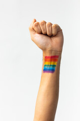 Close up of hand of biracial man clenching fist with rainbow flag on white background