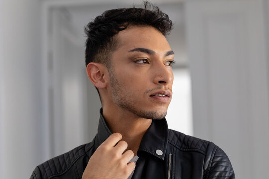 Biracial transgender man wearing white t-shirt and biker jacket, looking away - Powered by Adobe