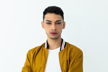 Portrait of biracial transgender man wearing make-up, looking at camera on white background