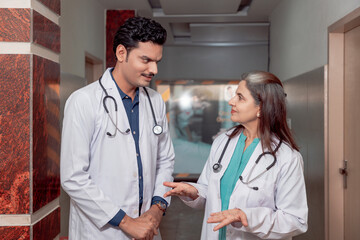 Senior female doctor discussing to assistance doctor at hospital.