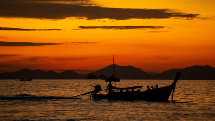 Sunset in the sea with a boat, in Ao Nang, Thailand.