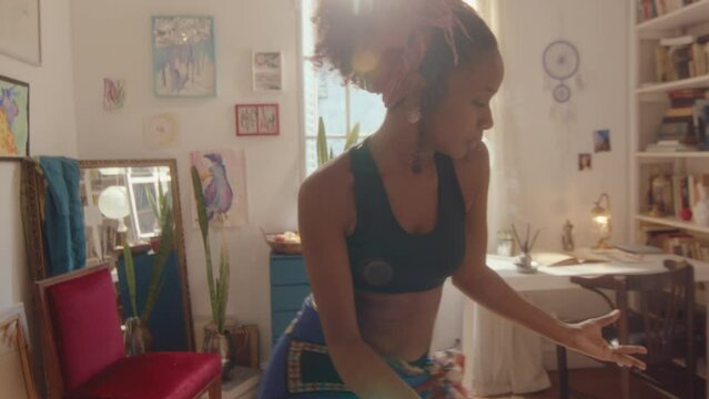 Young talented black female dancer dancing with inspiration in the living room on a sunny day, making choreo and enjoying the vibe