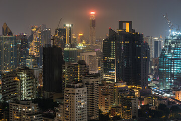Fototapeta premium Night cityscape skyline of modern illuminated asian Bangkok city with glowing skyscrapers and buildings glowing in twilight. Real estate and build of metropolis. Urban sprawl and development