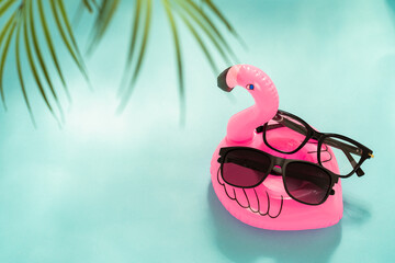 Summer sunglasses and glasses special offer, sale. Trendy sunglasses on inflatable flamingo on blue...