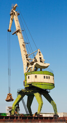 Yellow green portal crane stands in coal port area, close up