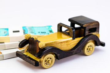 High angle close up shot of a wooden vintage toy car with money bundles defocused behind.