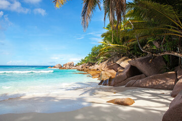 Naklejka na ściany i meble Scenic view of a tropical sandy beach with granite boulders and coconut palms. Seychelles. Indian Ocean.
