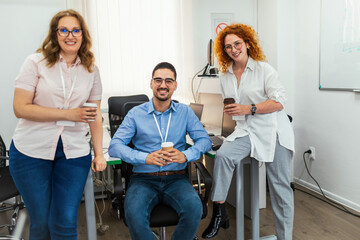 Obraz premium Happy business people stand together in the office and drink coffee to go.