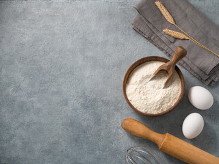 Ingredients for baking, wheat flour, eggs, rolling pin and kitchen textiles on a blue background....
